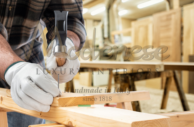 Worker with gloves and hammer applying nails on wood for carpentry products Modenese