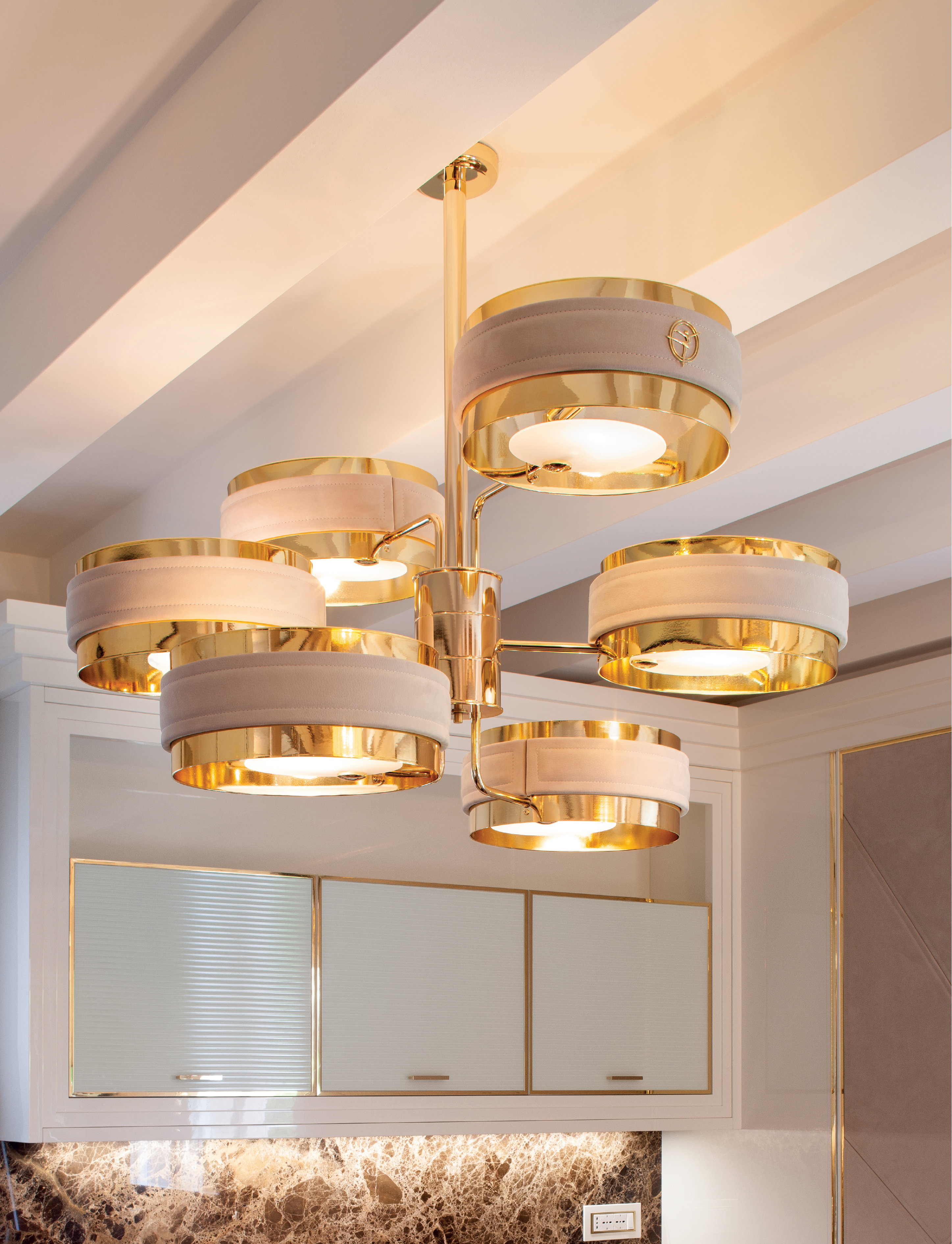 Gold-finished pendant lighting above ivory cabinetry in a luxury Abu Dhabi kitchen