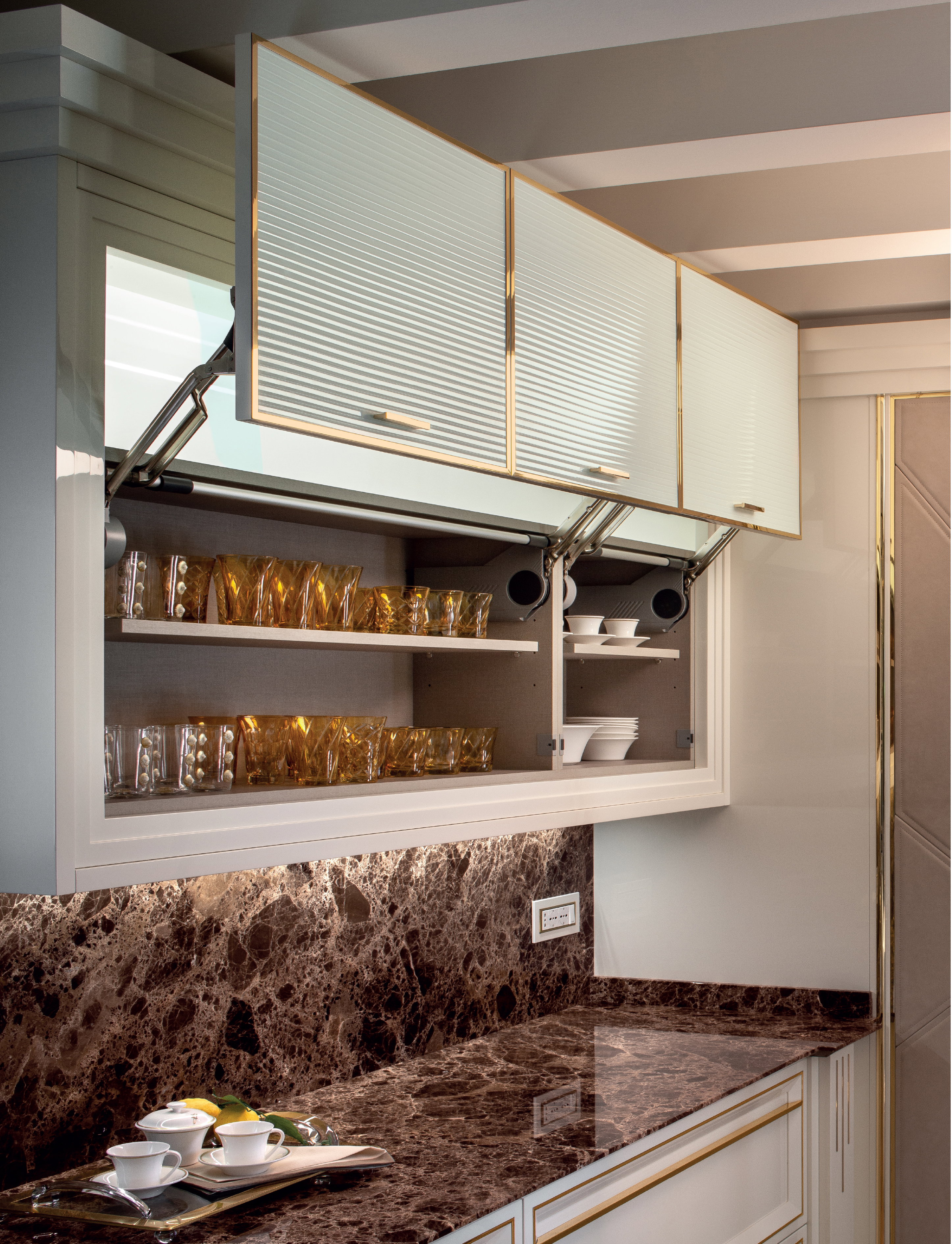 Lift-up wall cabinet doors and illuminated storage above a marble backsplash, Prestige kitchen